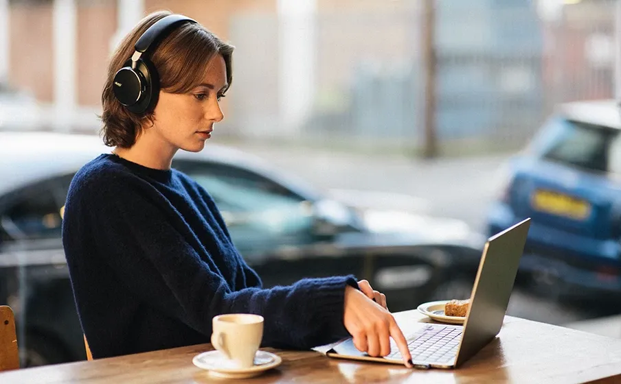 Mujer trabajando en un café con los audífonos AKG N9 Hybrid negros