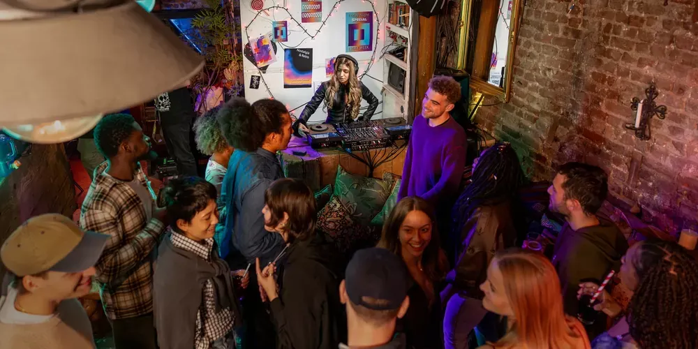 DJ tocando en un bar pequeño con el público alrededor de la cabina