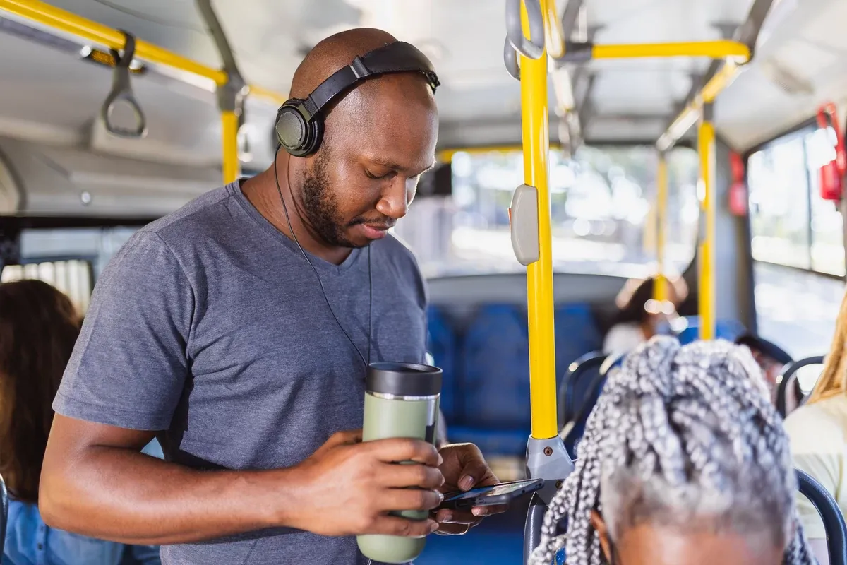 Mujer escuchando música con audífonos Bluetooth en el bus