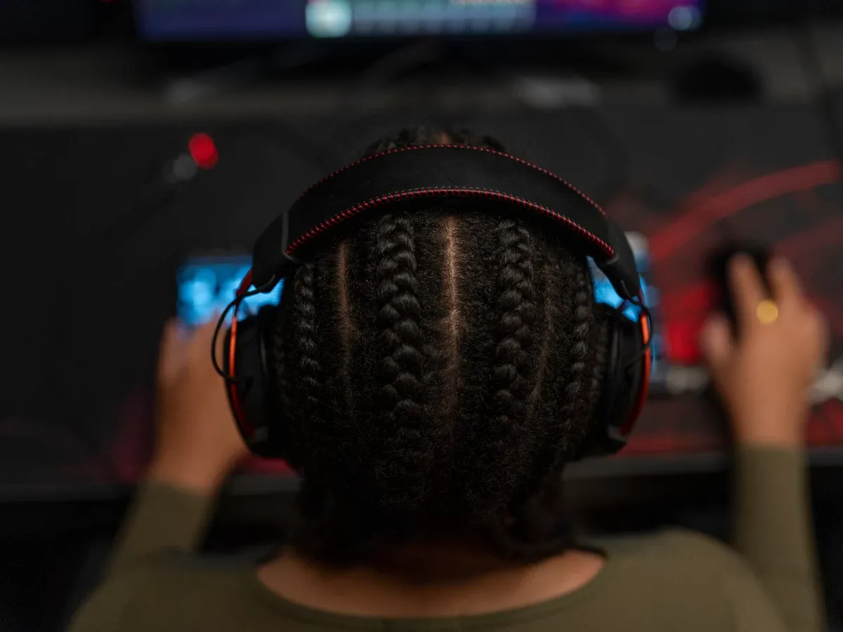 Jugadora con audífonos Bluetooth sin cable frente al computador