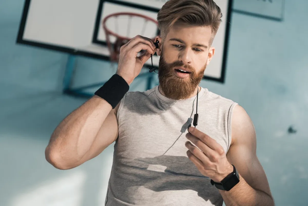 Hombre entrenando en el gimnasio con audífonos deportivos