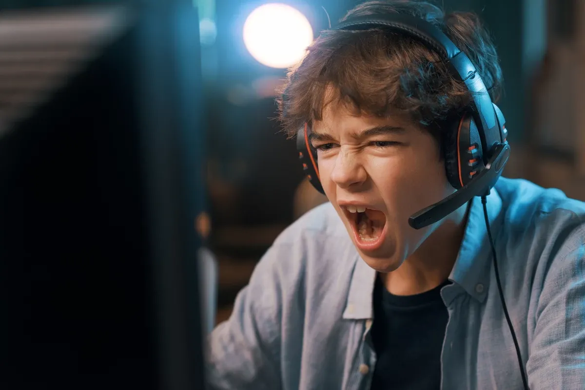 Jugador con aud&iacute;fonos gamer frente al computador