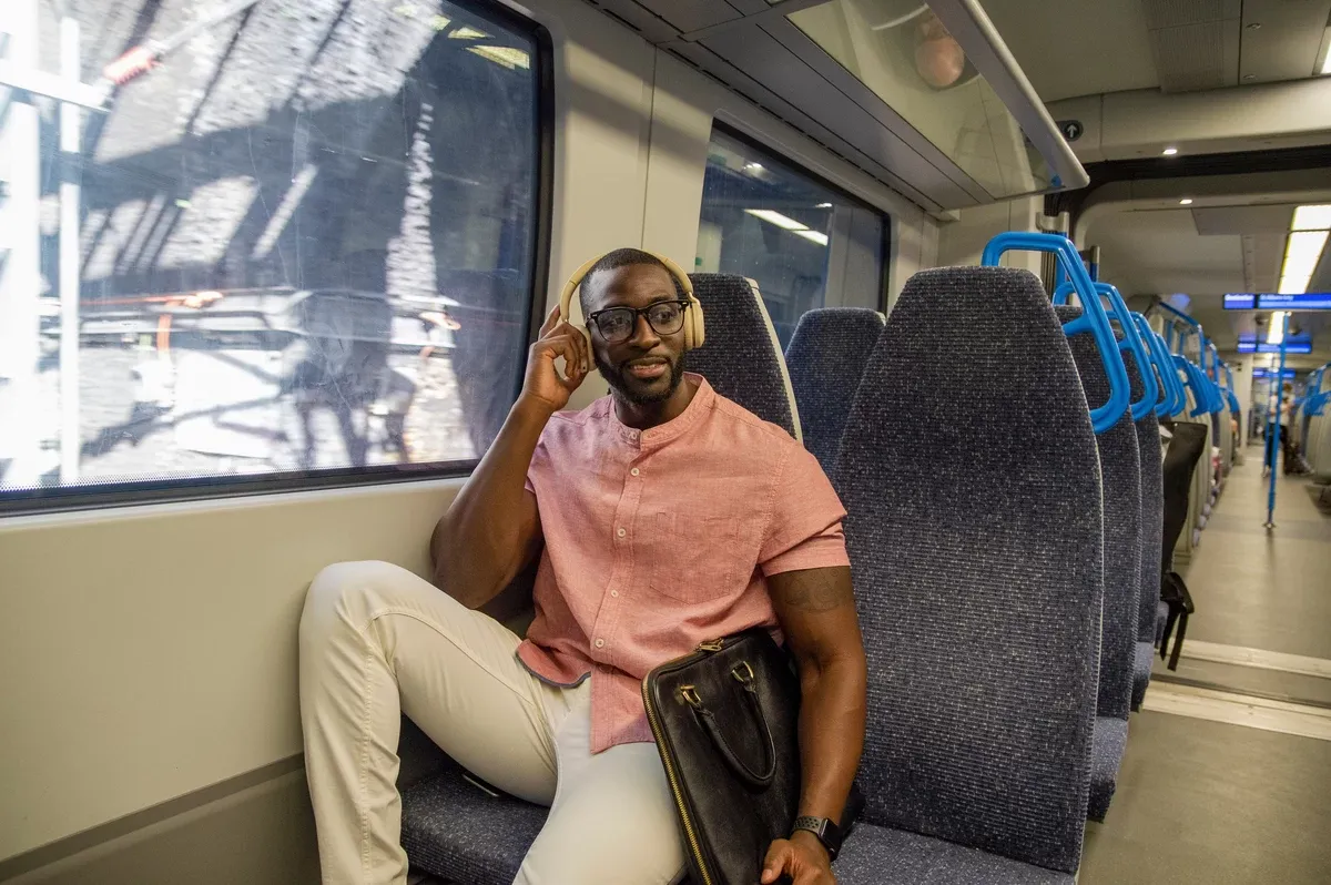 Hombre en el tren con el tel&eacute;fono y aud&iacute;fonos de o&iacute;do abierto