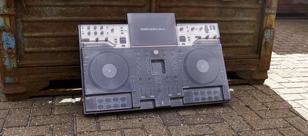Denon DJ Prime 4 G2 con la tapa Decksaver puesta, apoyado contra una pared