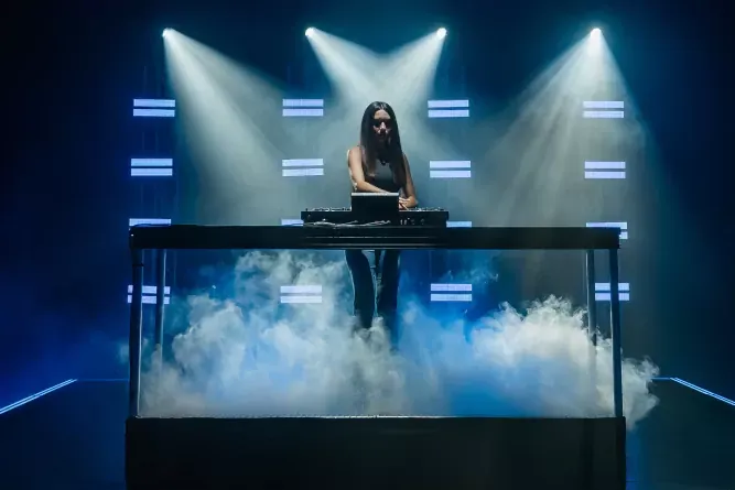 DJ tocando con el PRIME 4 G2 en un escenario con luces y humo