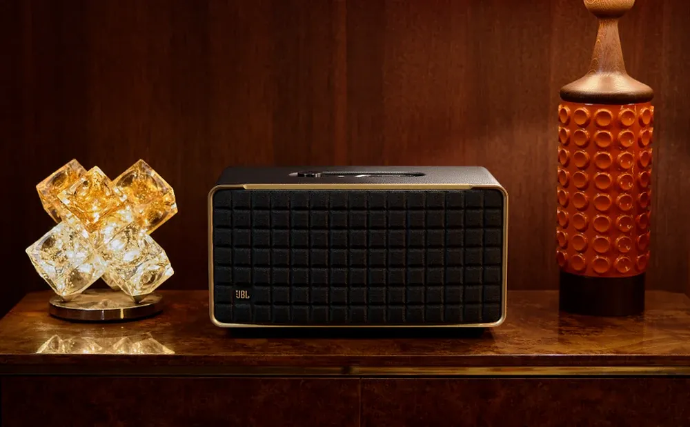 JBL Authentics 500 sobre un mueble de madera junto a una lámpara