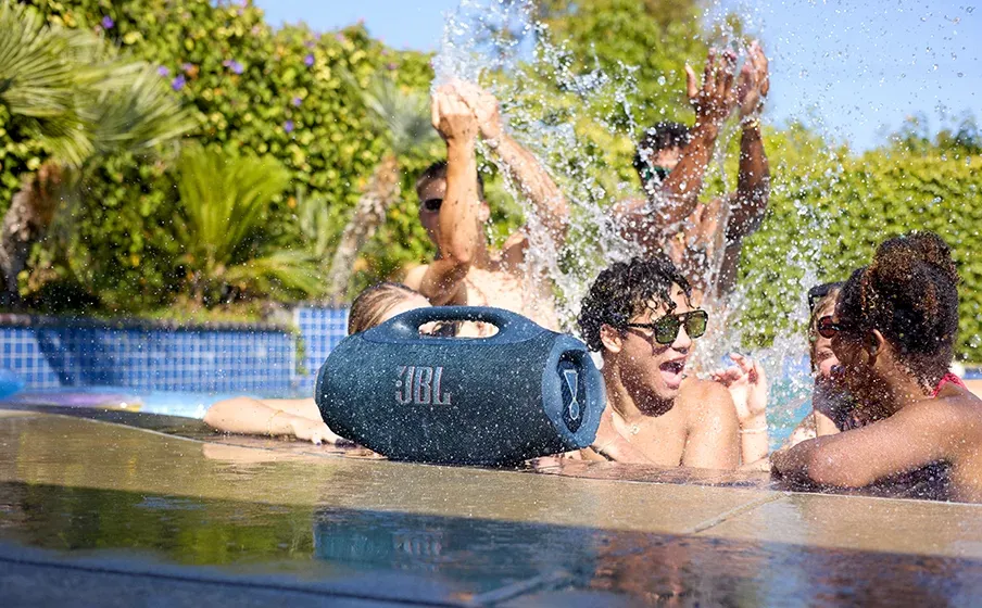 JBL Boombox 4 en el borde de una piscina con gente bañándose