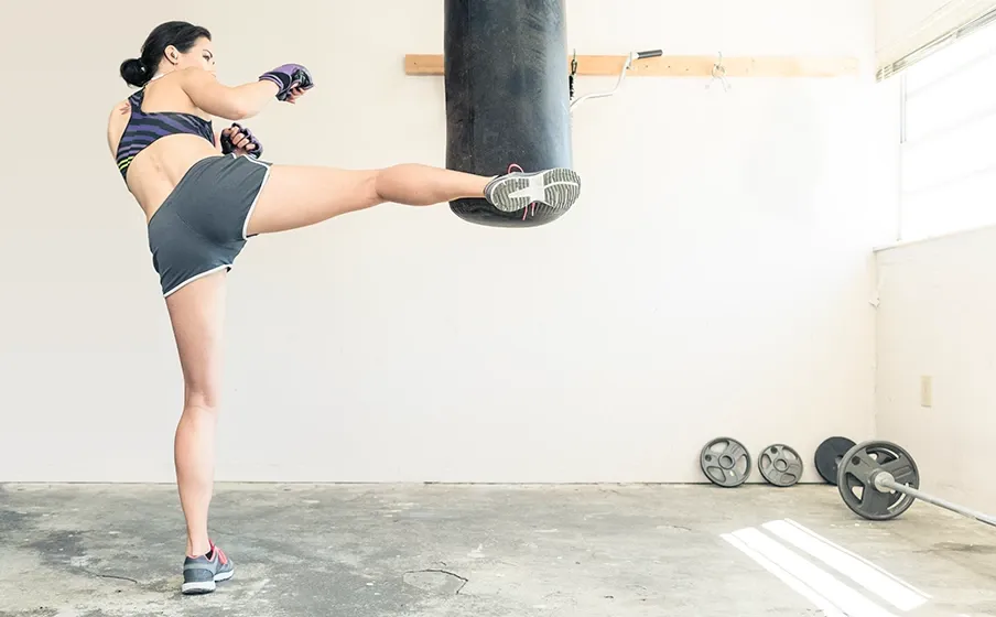 Mujer entrenando con saco de boxeo con audífonos JBL Endurance Run 3
