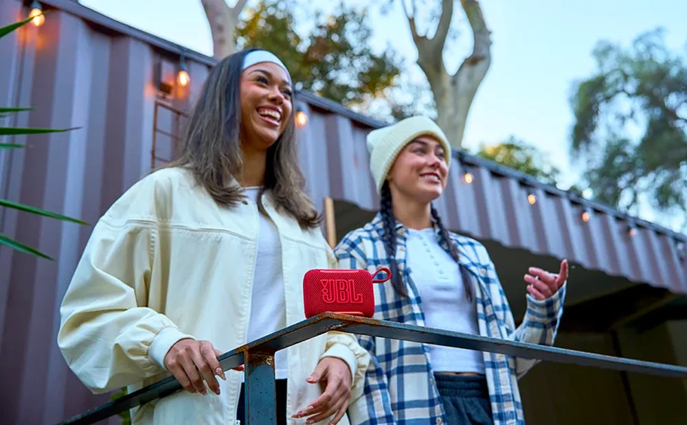 Dos personas caminando con el JBL Go 5 en la mano