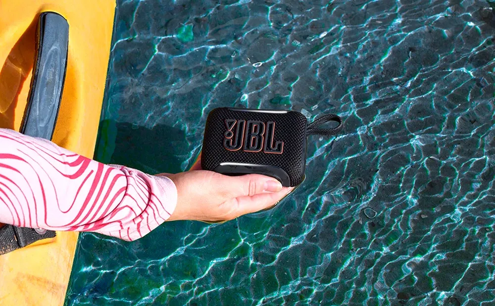 Mano sacando el JBL Go 5 del agua de una piscina