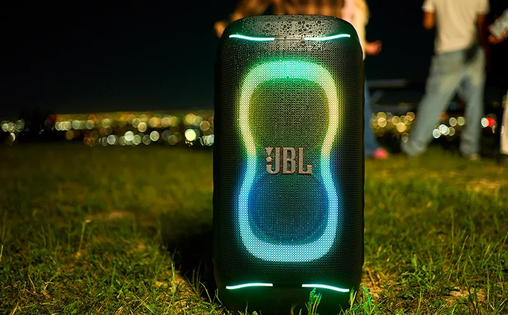 JBL PartyBox 130 iluminado de noche sobre el pasto