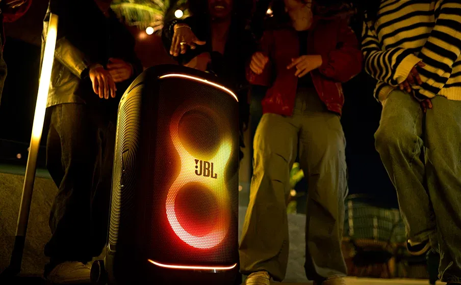 Grupo bailando junto al JBL PartyBox 520 con luces naranjas