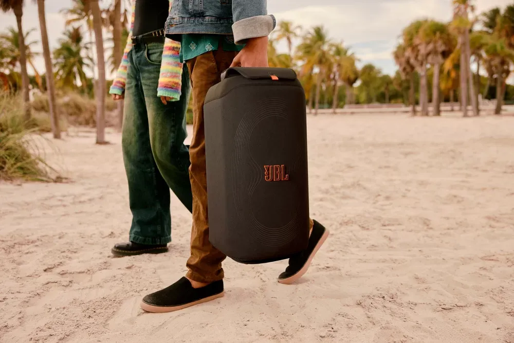 Persona llevando un PartyBox con su funda por la playa