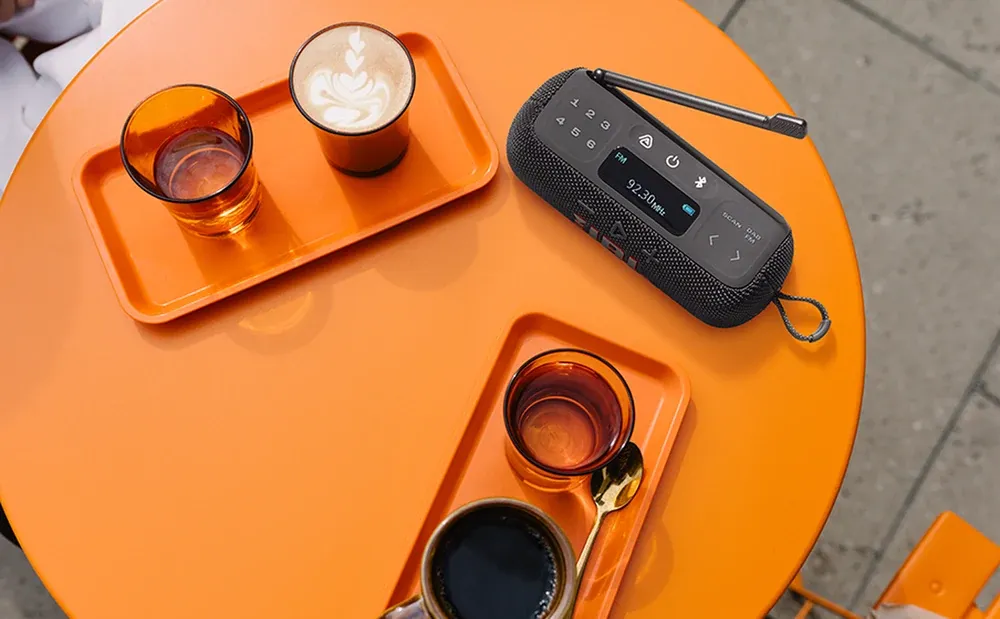 JBL Tuner 3 sobre una mesa de terraza junto a una bandeja con tazas