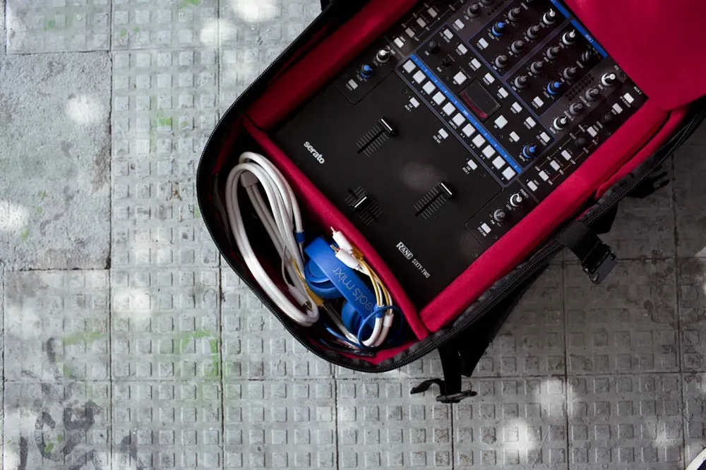 Interior rojo acolchado de una mochila Magma RIOT con mixer DJ, cables y audífonos