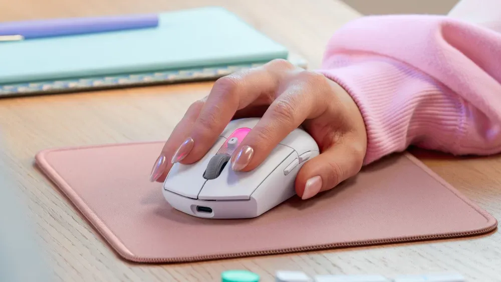 Mano usando el Logitech G305 X SUPERLIGHT blanco sobre un mouse pad rosado