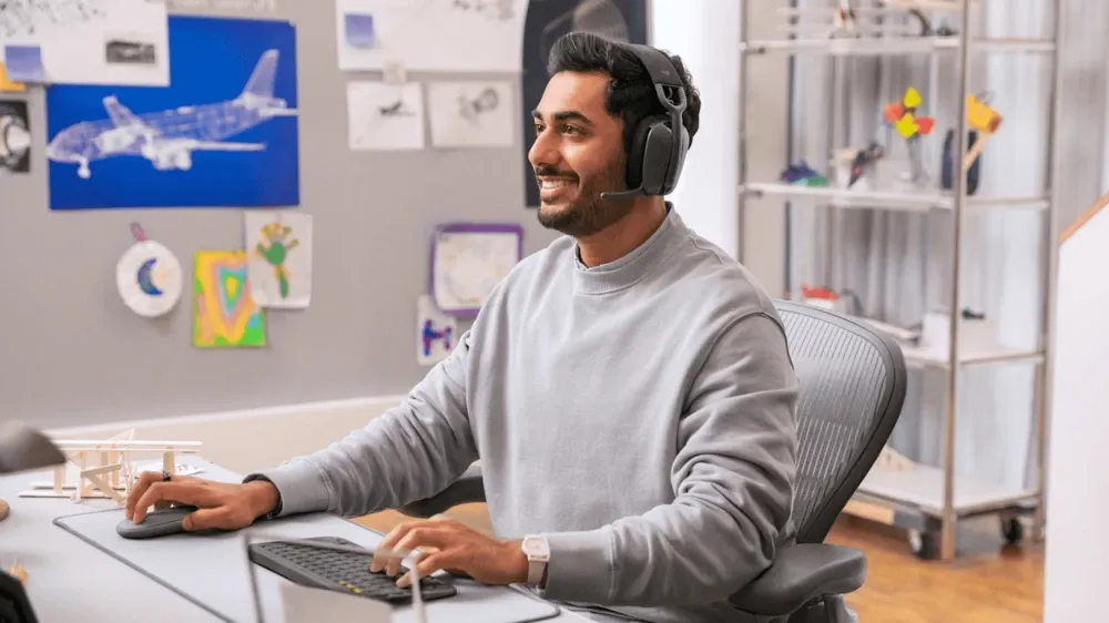 Hombre sonriendo frente al computador con los Logitech Zone Vibe Wireless