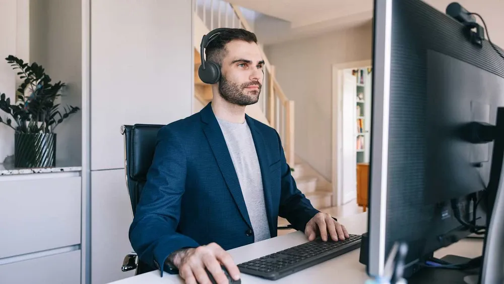 Hombre trabajando en su escritorio con los Logitech Zone Wireless 2 ES grafito
