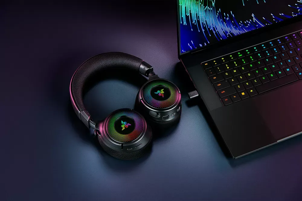 Dongle USB-C HyperSpeed del Razer Kraken V4 conectado a un notebook, junto a los audífonos